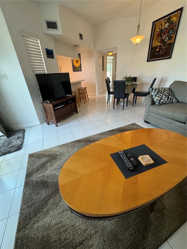 living area with tile patterned flooring, visible vents, and lofted ceiling