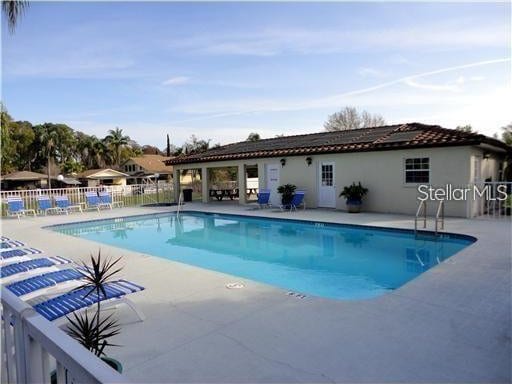 community pool with a patio and fence