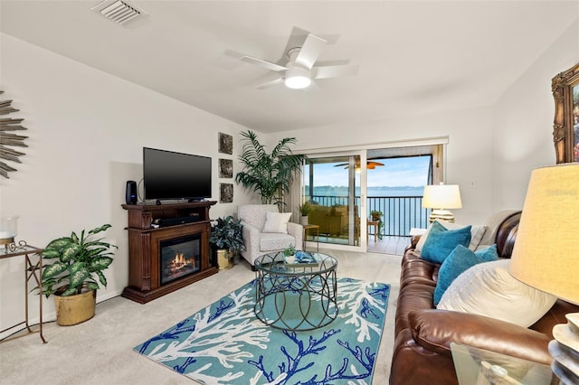 living room with light colored carpet, a glass covered fireplace, visible vents, and ceiling fan