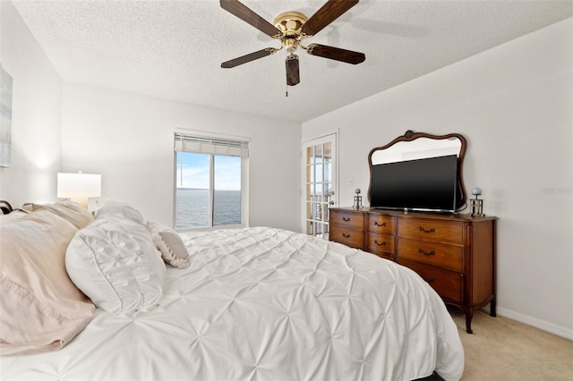 bedroom featuring light carpet, ceiling fan, a textured ceiling, and baseboards