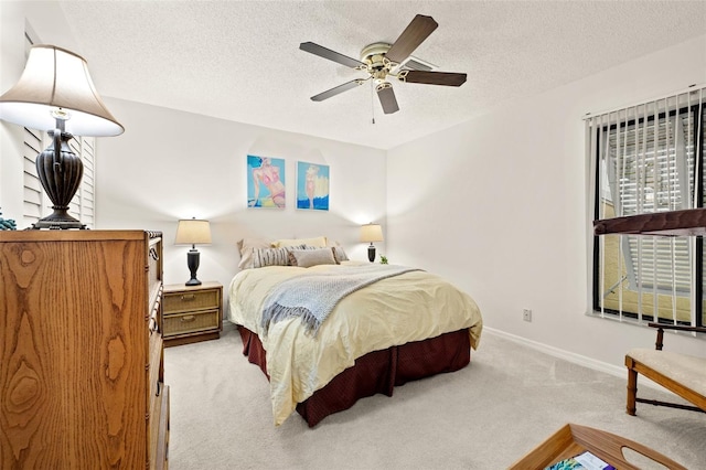 bedroom featuring a ceiling fan, light colored carpet, a textured ceiling, and baseboards