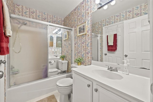 bathroom with combined bath / shower with glass door, vanity, toilet, and wallpapered walls