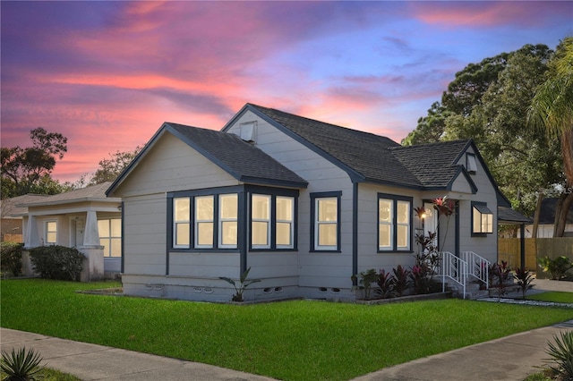 bungalow-style house featuring crawl space, a shingled roof, and a front lawn