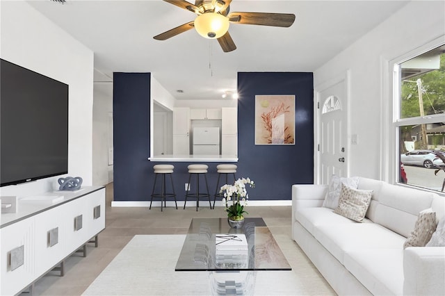 living room featuring light tile patterned floors, ceiling fan, and baseboards