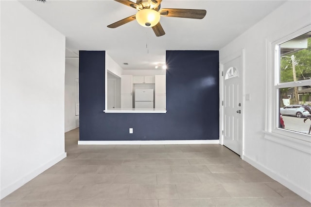 spare room featuring ceiling fan and baseboards