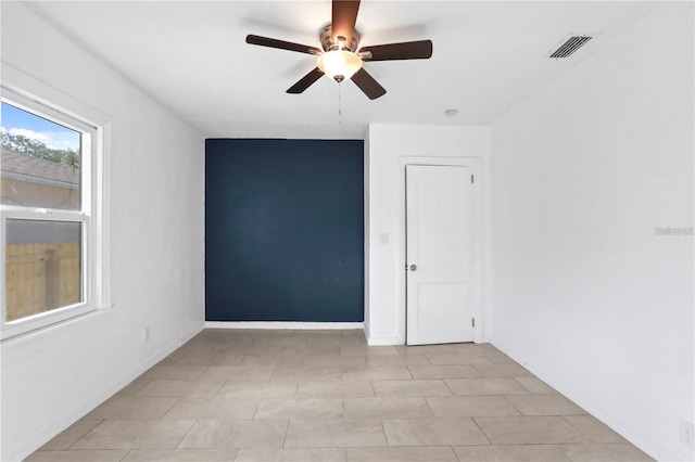 empty room featuring a ceiling fan, visible vents, and baseboards