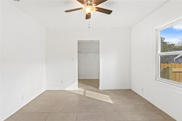 unfurnished bedroom with baseboards, ceiling fan, tile patterned flooring, a walk in closet, and a closet