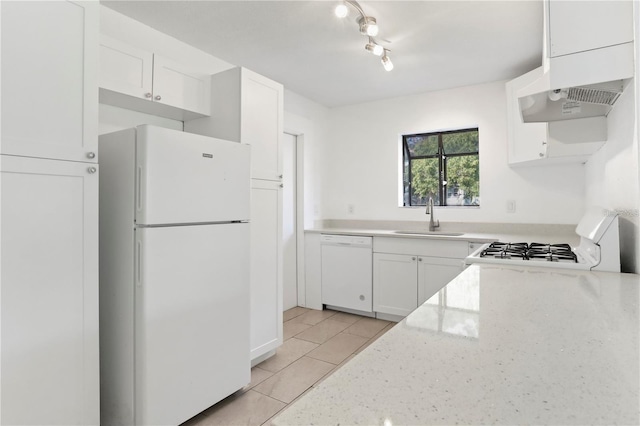 kitchen with light stone counters, light tile patterned flooring, white appliances, a sink, and white cabinets