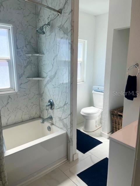 bathroom featuring marble finish floor, vanity, toilet, and bathtub / shower combination