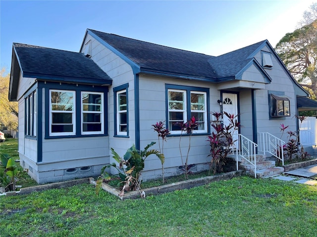 bungalow featuring a front yard and roof with shingles