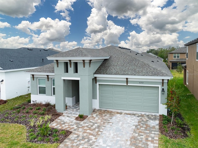 view of front of property with a garage, decorative driveway, a shingled roof, and stucco siding