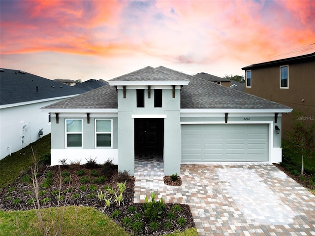 view of front of home with a garage, a shingled roof, decorative driveway, and stucco siding