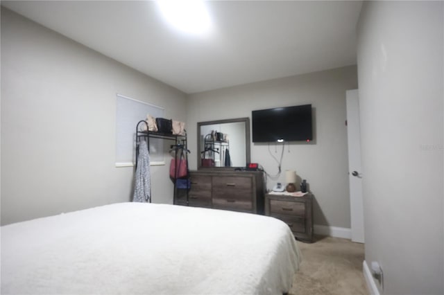 bedroom featuring light carpet and baseboards