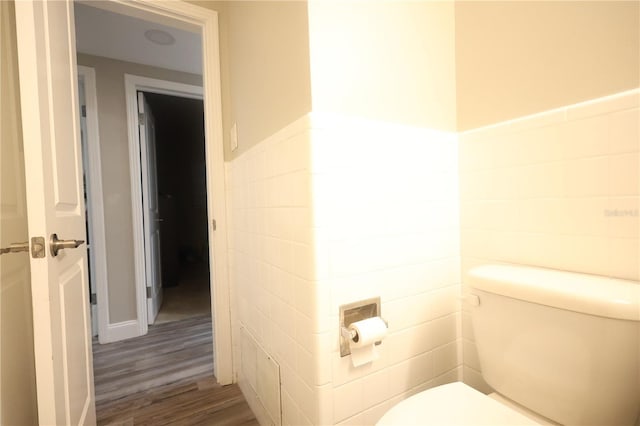 bathroom featuring toilet, a wainscoted wall, tile walls, and wood finished floors