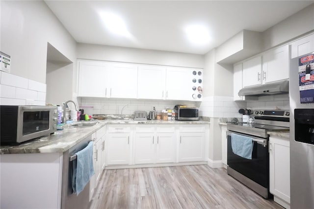 kitchen featuring under cabinet range hood, stainless steel appliances, a sink, white cabinets, and light wood finished floors