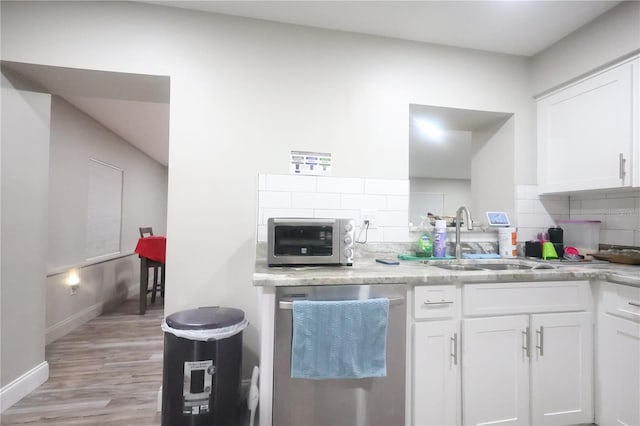 kitchen with tasteful backsplash, white cabinetry, a sink, and stainless steel dishwasher