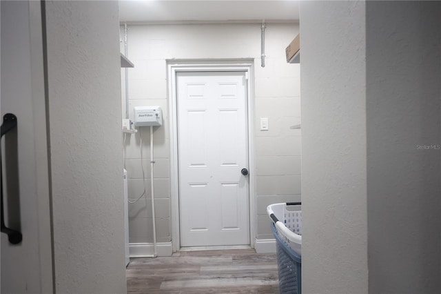 bathroom with concrete block wall and wood finished floors