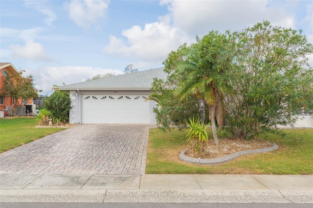 view of front of home with a garage, a front lawn, decorative driveway, and a shingled roof