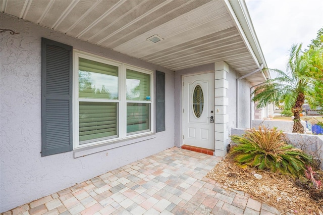 view of exterior entry with a patio area and stucco siding