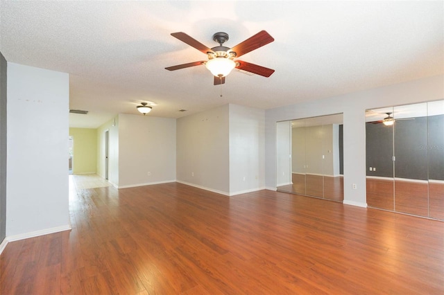 unfurnished room with visible vents, a ceiling fan, a textured ceiling, wood finished floors, and baseboards