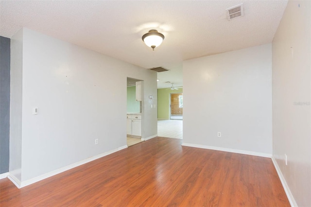 unfurnished room featuring visible vents, ceiling fan, baseboards, and wood finished floors