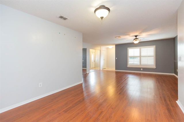 empty room with baseboards, visible vents, ceiling fan, and wood finished floors