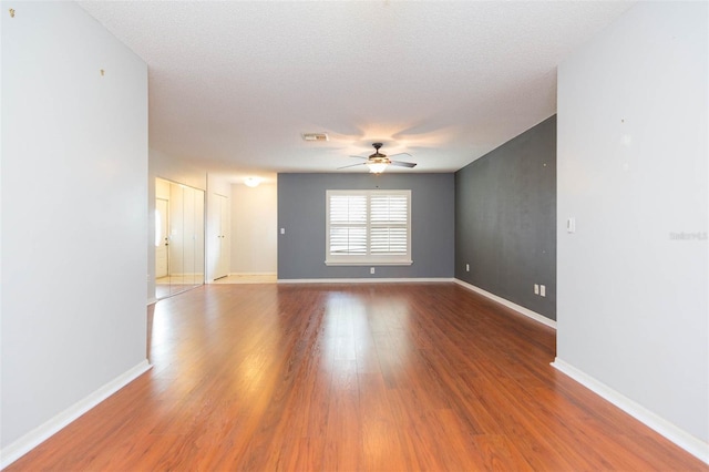 spare room with baseboards, a textured ceiling, a ceiling fan, and wood finished floors