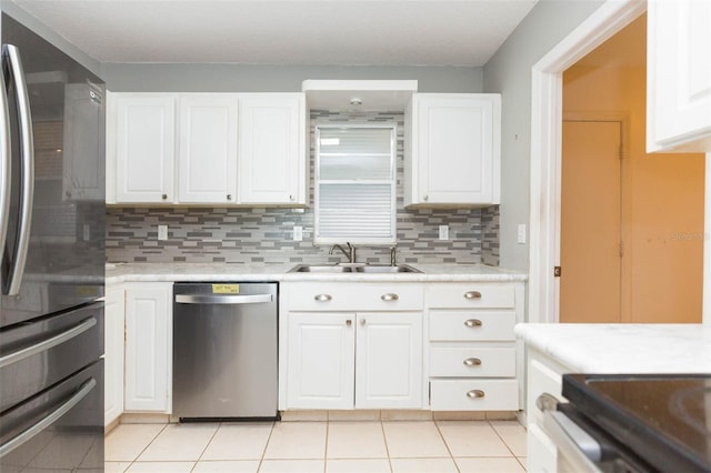 kitchen featuring appliances with stainless steel finishes, white cabinets, light countertops, and a sink