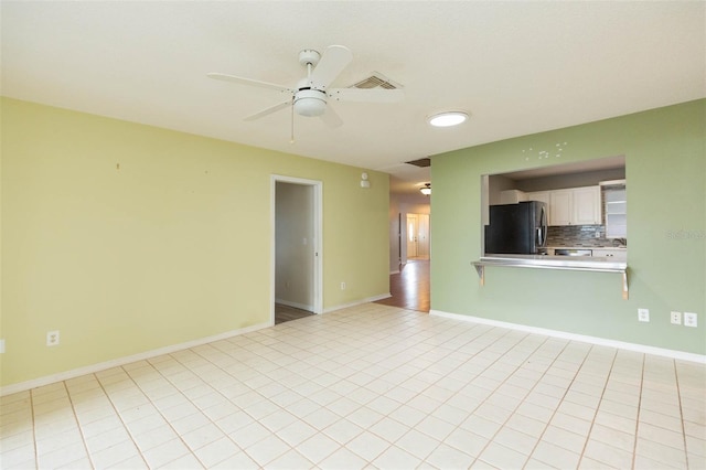 spare room with baseboards, visible vents, ceiling fan, and light tile patterned flooring