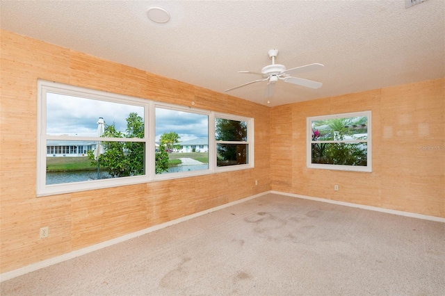 spare room with a textured ceiling, carpet, a ceiling fan, and baseboards