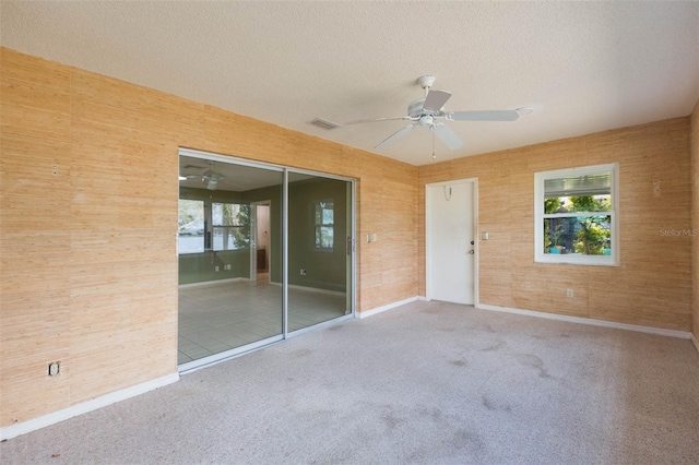 carpeted empty room featuring a healthy amount of sunlight, ceiling fan, and a textured ceiling