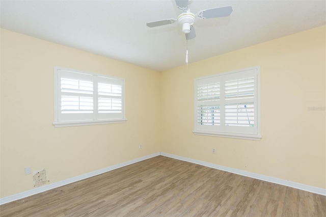 empty room with a ceiling fan, light wood-type flooring, and baseboards