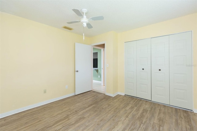 unfurnished bedroom with light wood finished floors, baseboards, visible vents, ceiling fan, and a closet