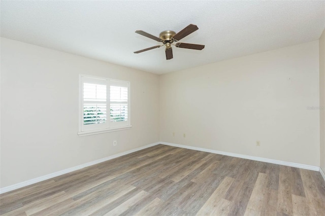 unfurnished room with light wood-type flooring, ceiling fan, baseboards, and a textured ceiling