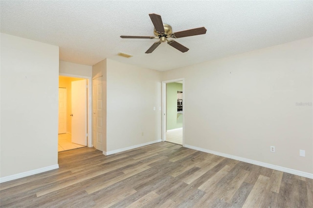 unfurnished room with a textured ceiling, baseboards, and wood finished floors