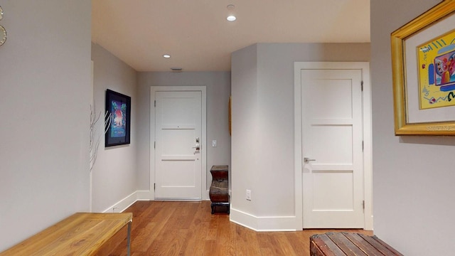 hallway with baseboards, wood finished floors, and recessed lighting