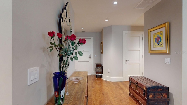 hallway with baseboards, light wood finished floors, visible vents, and recessed lighting