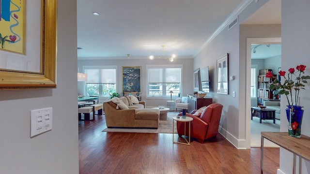 living area with crown molding, visible vents, baseboards, and wood finished floors