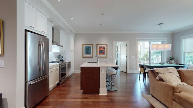 kitchen featuring dark wood-style flooring, stainless steel appliances, a sink, an island with sink, and a kitchen bar