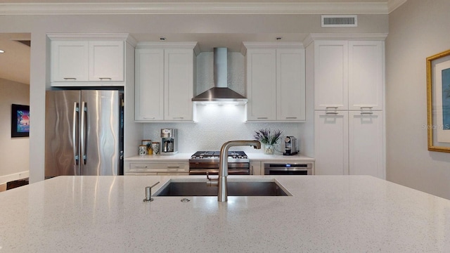 kitchen featuring appliances with stainless steel finishes, visible vents, crown molding, and wall chimney exhaust hood