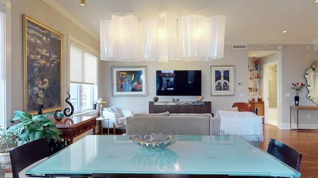 dining space with baseboards, visible vents, crown molding, and wood finished floors