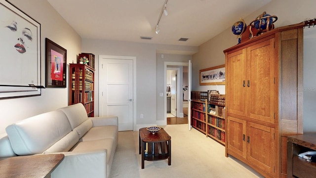 living area with rail lighting, light carpet, and visible vents