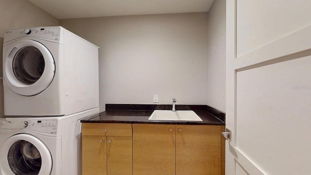 laundry area featuring stacked washer and dryer, a sink, and cabinet space