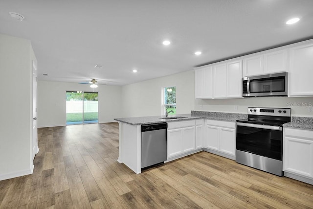 kitchen with open floor plan, stainless steel appliances, and white cabinetry