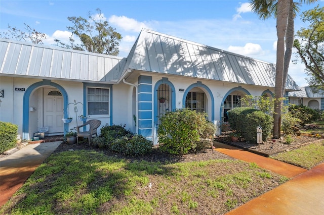 view of front of house with a front yard, metal roof, and stucco siding