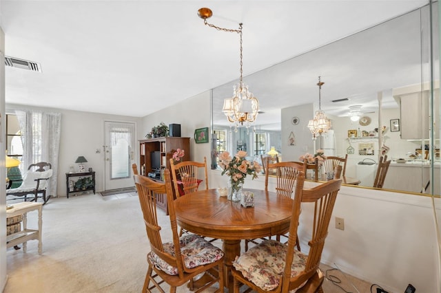 dining space featuring a chandelier, light carpet, and visible vents