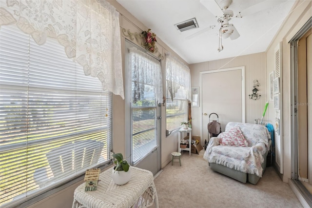 sitting room with a ceiling fan, visible vents, and light colored carpet