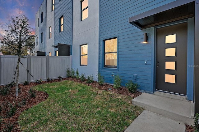 property entrance featuring fence and a lawn