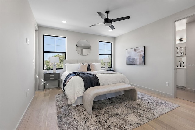 bedroom with light wood finished floors, recessed lighting, a sink, and baseboards