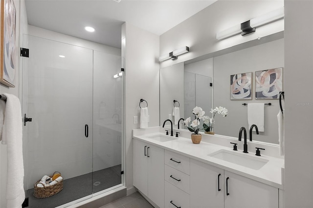 full bathroom with double vanity, tile patterned flooring, a sink, and a shower stall